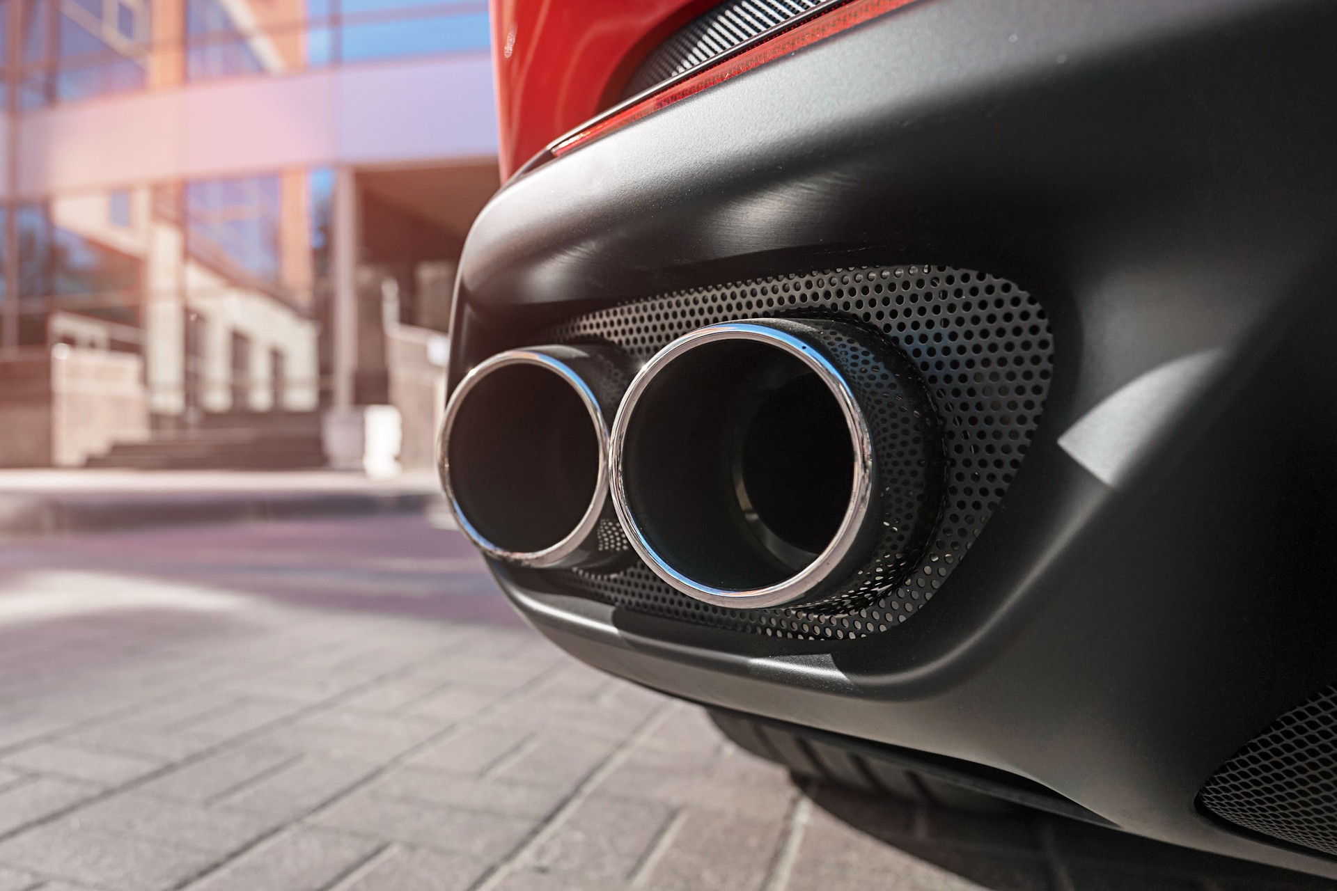 Modern chrome dual sport car muffler fixed in automobile bumper.