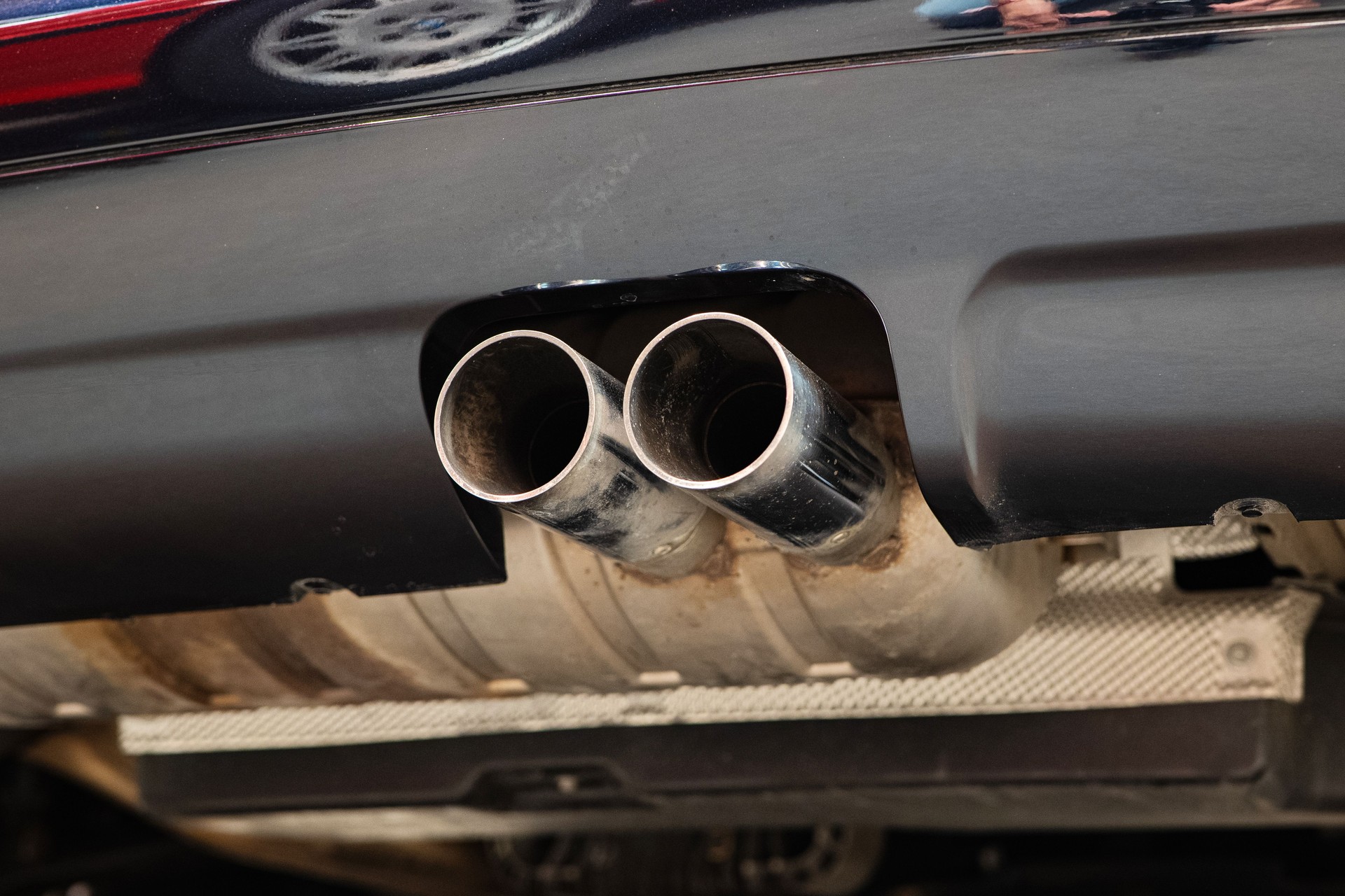 Twin tip car exhaust pipe or tail pipe. Low angle view, chromed metal, no people